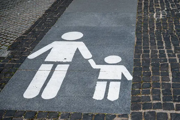 Kaldırıma bir yaya sembolü çizilmiş, stilize bir yetişkinin bir çocuğun elini tuttuğunu gösteren bir yürüyüş yolu..