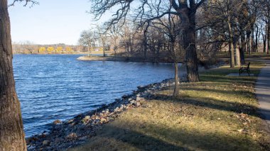 Göl kenarındaki sonbahar parkında yürü. Altın yapraklar, sükunet, suyun yansımaları, temiz hava ve doğanın güzelliği..