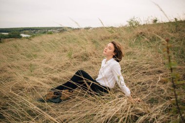 Moda mankeni, doğada huzurlu bir anın tadını çıkarıyor. Kapalı gözlerle kuru otların arasında oturuyor.