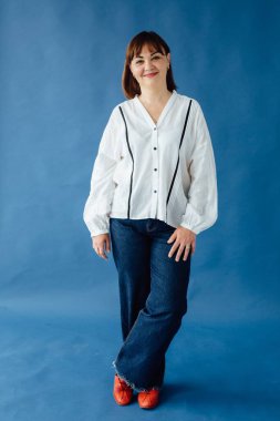 40 'lı yaşlarda bir iş kadınının stüdyo portresi, canlı mavi bir arka plana karşı şık ve rahat bir kıyafet giyiyor.