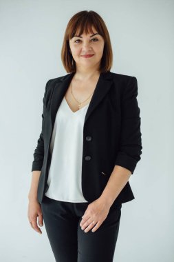 40 'larında, kendine güvenen bir iş kadınının, siyah takım elbise ve beyaz gömlek giymiş, profesyonellik ve başarı saçan bir stüdyo portresi.