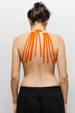 Sırtında bantlarla beyaz arka planda bir bayan sporcu. 