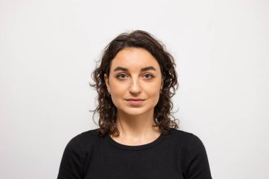 A beautiful woman on a white background looks directly into the camera 