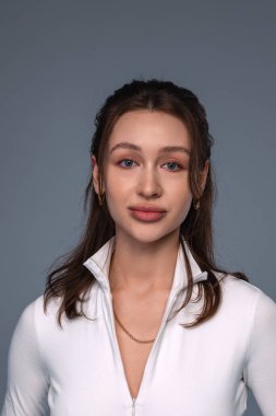 Portrait of a beautiful young girl on a gray background in the studio with light makeup and accessories