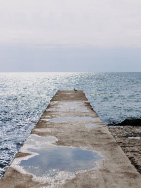Güneşli bir günde, deniz kıyısında beton, paslı bir demir.