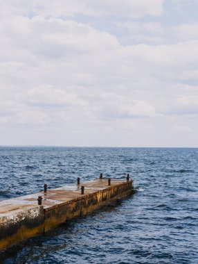 Güneşli bir günde, deniz kıyısında beton, paslı bir demir.
