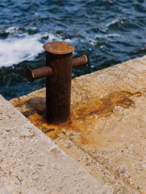 Güneşli bir günde, deniz kıyısında beton, paslı bir demir.