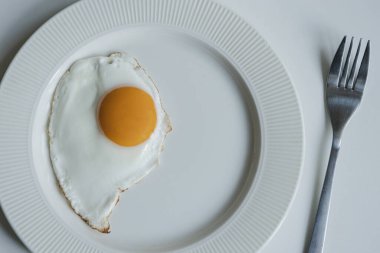 Beyaz bir masada hafif bir kahvaltı, sade bir yumurta ve sade kahve..