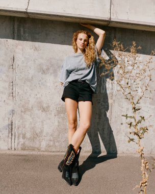 Güzel ve şık bir kız, kıvırcık saçlı sokaklarda yürüyor. 