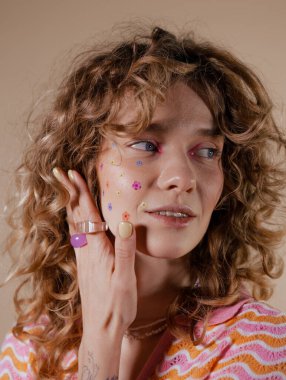 Kıvırcık saçlı ve makyajlı güzel ve çekici bir kız. Duygusal olarak 90 'ların tarzında poz veriyor.