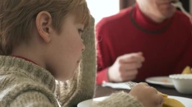 Çocuklu Genç Aile Kahvaltı Yemeği Yiyin. Baba Anne Çocuk birlikte yemek yiyor. Masada Taze Kızarmış Patates Tabağı. 2x Yavaş çekim 60 fps 4K