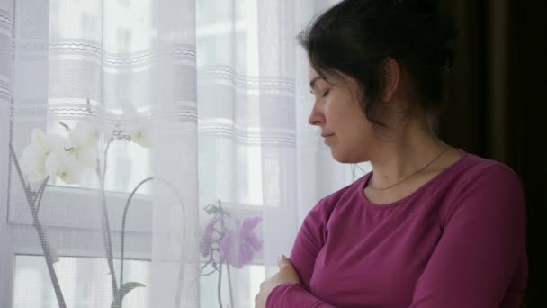 Concerned Distressed Woman Stands Thinking Looking Out Window Sad Expression — Stock Video