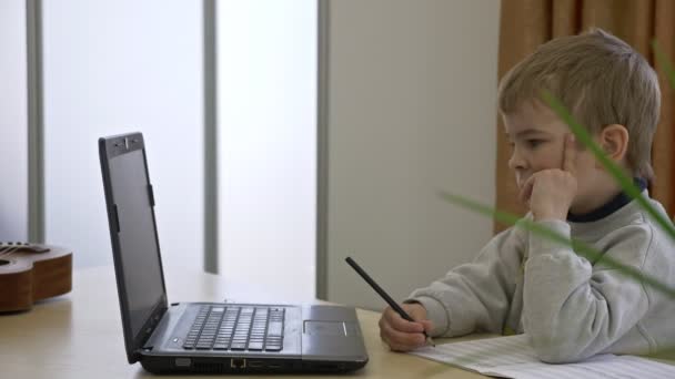 Маленький Мальчик Дистанционно Изучает Онлайн Музыку Дома Сидя Письменным Столом — стоковое видео