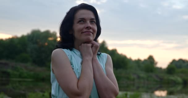 幸せな女性は川の近くの自然の中でリラックスした休息をお楽しみください 夏の夕日 田園風景 — ストック動画