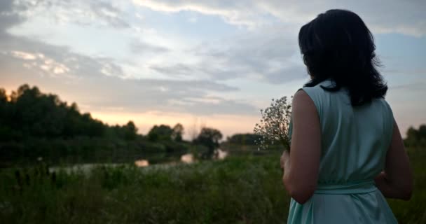 Жінка Квітами Спостерігає Заходом Сонця Насолоджуючись Відпочинком Природі Біля Річки — стокове відео