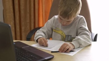 Kid Erases Mistakes with Rubber Eraser. Little Boy Distance Remote Study  Music Online on Laptop at Home Sitting at Desk. Slow motion 4K