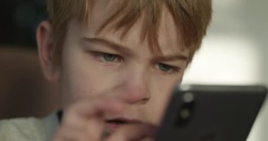 Ciddi Çocuk Akıllı Telefona İsteyerek ve Özenli Bakıyor. Çocuk Arıyor ve Akıllı Telefon Oynuyor. 4K Ağır çekim 10-bit