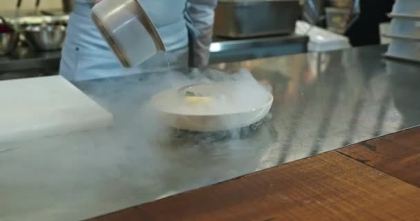 男性の手は絶妙な皿に液体窒素を注ぎます シェフ クックは美味しい食事を用意しています レストランキッチンでの調理プロセス 10ビット スローモーション — ストック動画