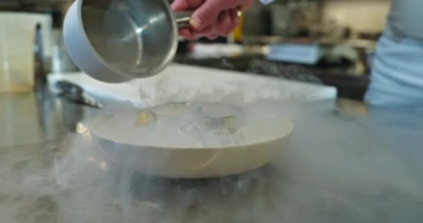 男性の手は絶妙な皿に液体窒素を注ぎます シェフ クックは美味しい食事を用意しています レストランキッチンでの調理プロセス 10ビット スローモーション — ストック動画