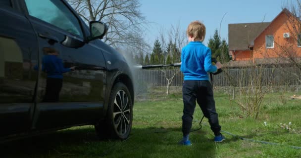 아이는 자동차 와셔를 사용하여 뒤뜰에서 자동차를 청소합니다 아이는 차량을 세척하는 — 비디오