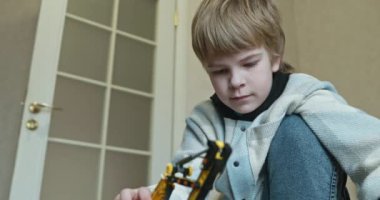 Küçük Çocuk Uzaktan Kumanda 'da Oyuncak Kazıcı' yı oynuyor. Evde Yatakta Oynayan Çocuk. 4K 10-bit