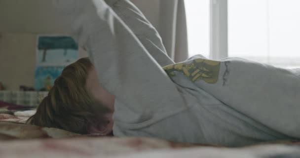 Kid Boy Robi Ćwiczenia Hantlami Domu Dziecko Ćwiczy Leżąc Łóżku — Wideo stockowe