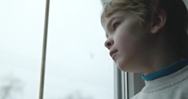 Üzgün Çocuk Dalgın Bakış. Pencereden dışarı bakan yalnız çocuk. Çocuk Üzgün Düşünceli Endişeli Kayıp Duygu. 4K 10-bit