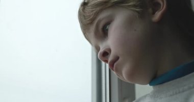 Üzgün Çocuk Dalgın Bakış. Pencereden dışarı bakan yalnız çocuk. Çocuk Üzgün Düşünceli Endişeli Kayıp Duygu. 4K 10-bit