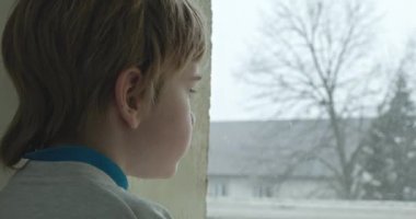 Üzgün Çocuk Dalgın Bakış. Pencereden dışarı bakan yalnız çocuk. Çocuk Üzgün Düşünceli Endişeli Kayıp Duygu. 4K 10-bit