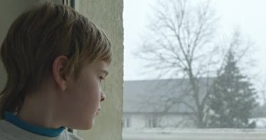 Üzgün Çocuk Dalgın Bakış. Pencereden dışarı bakan yalnız çocuk. Çocuk Üzgün Düşünceli Endişeli Kayıp Duygu. 4K 10-bit