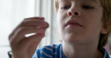 Çocuk evdeki mutfakta tereyağlı ve yeşil zeytinli ekmek yiyor. 4K 10-bit