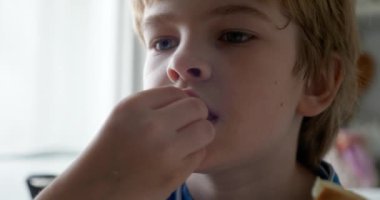 Çocuk evdeki mutfakta tereyağlı ve yeşil zeytinli ekmek yiyor. 4K 10-bit