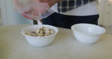 Man Pistachio ve Fıstıkları Dish 'e döker. Yavaş çekim 60 fps 4K