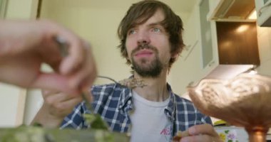 Beyaz Kafkasyalı adam mutfakta sağlıklı vejetaryen yemeği yiyor. Yavaş çekim 60fps 4K 10-bit