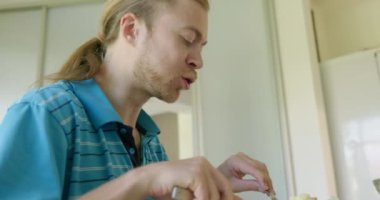 Beyaz Kafkasyalı adam mutfakta sağlıklı vejetaryen yemeği yiyor. Yavaş çekim 60fps 4K 10-bit