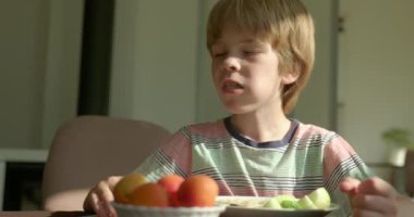 Tatlı çocuk kahvaltıda salatalık ve vejetaryen yemeğiyle spagetti yiyor. Yavaş çekim 60 fps 4K 10-bit