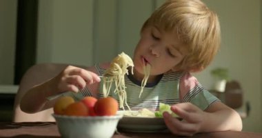 Tatlı çocuk kahvaltıda salatalık ve vejetaryen yemeğiyle spagetti yiyor. Yavaş çekim 60 fps 4K 10-bit