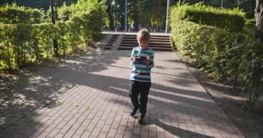 Akıllı Telefonlu Çocuk Şehir Parkı 'nda Tek Başına Yürüyor. Yaz Günü 4K 10-bit