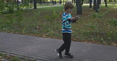 Akıllı Telefonlu Çocuk Şehir Parkı 'nda Tek Başına Yürüyor. Yaz Günü 4K 10-bit