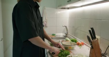 Bıçaklı Erkek El salata için yeşil bitkileri kesti. Mutfakta Bekar Adam Kahvaltı ya da Akşam Yemeği Hazırlıyor. Yavaş çekim 60fps 4K