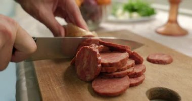 Bıçaklı sosisi dilimlere ayırır. Mutfakta Kafkas Adam Kahvaltı ya da Akşam Yemeği Hazırlıyor. Yavaş çekim 60fps 4K 10-bit