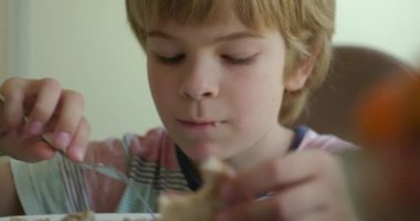 Çocuk çocuk akşam yemeğinde karabuğday lapası ve sandviç yiyor. Yavaş çekim 60fps 4K 10-bit