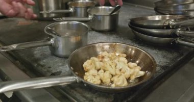 Karnabahar kızartma tavasında. Restoran Mutfağında Şef Cook 'tan yemek hazırlığı. Yavaş çekim 60fps 4K 10-bit