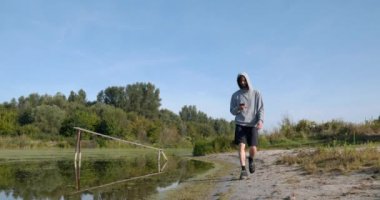 Kafkas Adam Akıllı Telefonla Nehir kenarında Yürüyor. Doğa yürüyüşü. Yavaş çekim 60fps 4K 10-bit