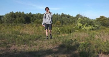 Kafkas Adam Akıllı Telefonla Nehir kenarında Yürüyor. Doğa yürüyüşü. Yavaş çekim 60fps 4K 10-bit