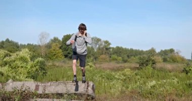 Kafkas Adam Akıllı Telefonla Nehir kenarında Yürüyor. Doğa yürüyüşü. Yavaş çekim 60fps 4K 10-bit