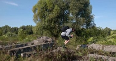 Kafkas Adam Akıllı Telefonla Nehir kenarında Yürüyor. Doğa yürüyüşü. Yavaş çekim 60fps 4K 10-bit