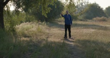 Mutlu Adam sabah doğada yürürken el sallıyor. 4K 10-bit.