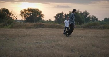 Man and Boy sahada koşuyor. Baba ve Çocuk Doğa 4K 10-bit 'te Birlikte Zaman Geçiriyorlar