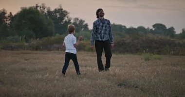 Man and Boy sahada koşuyor. Baba ve Çocuk Doğa 4K 10-bit 'te Birlikte Zaman Geçiriyorlar